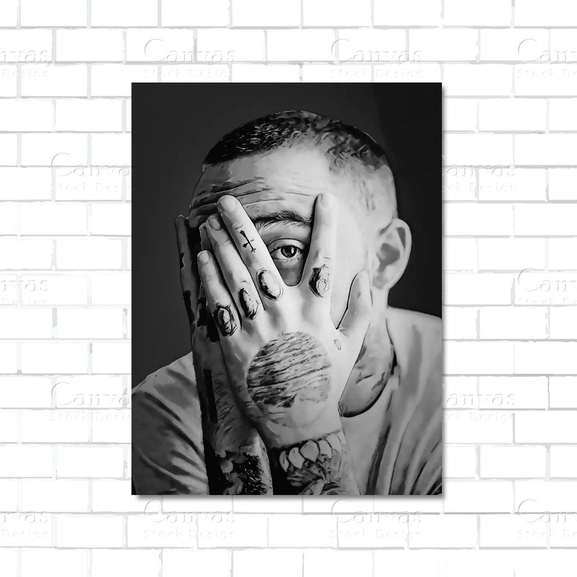 Black and white portrait of a person with tattoos on a hand against a white brick wall.