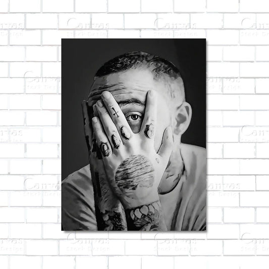 Black and white portrait of a person with tattoos on a hand against a white brick wall.